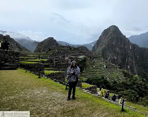 Maribel standing on one of the terraces at Machu Picchu with the ruins and mountains behind her.